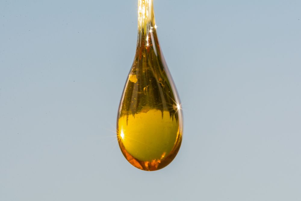 A close up of a drop of oil against a blue sky.
