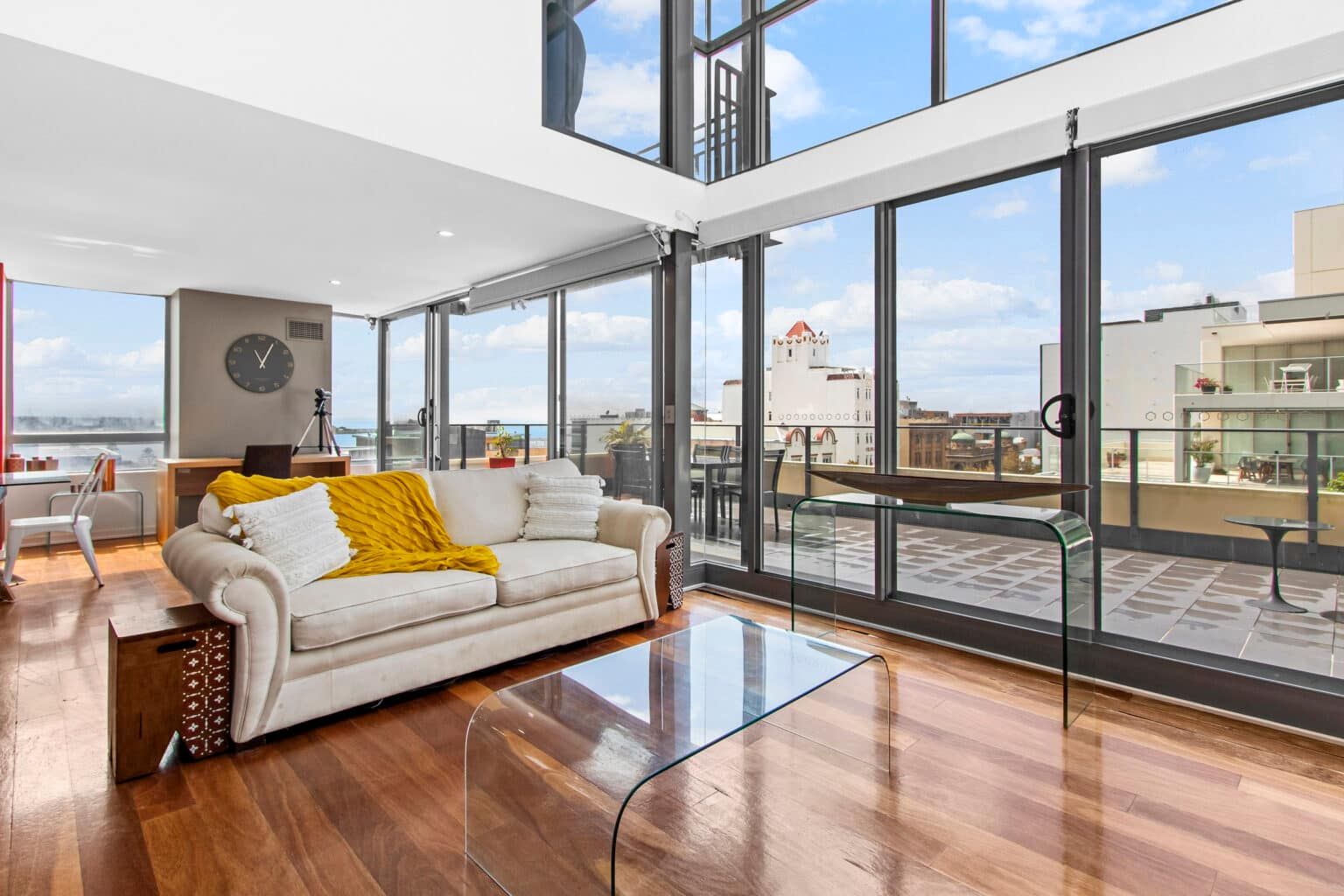 A living room with a couch , coffee table , and lots of windows — Maison Property Management in Mayfield, NSW