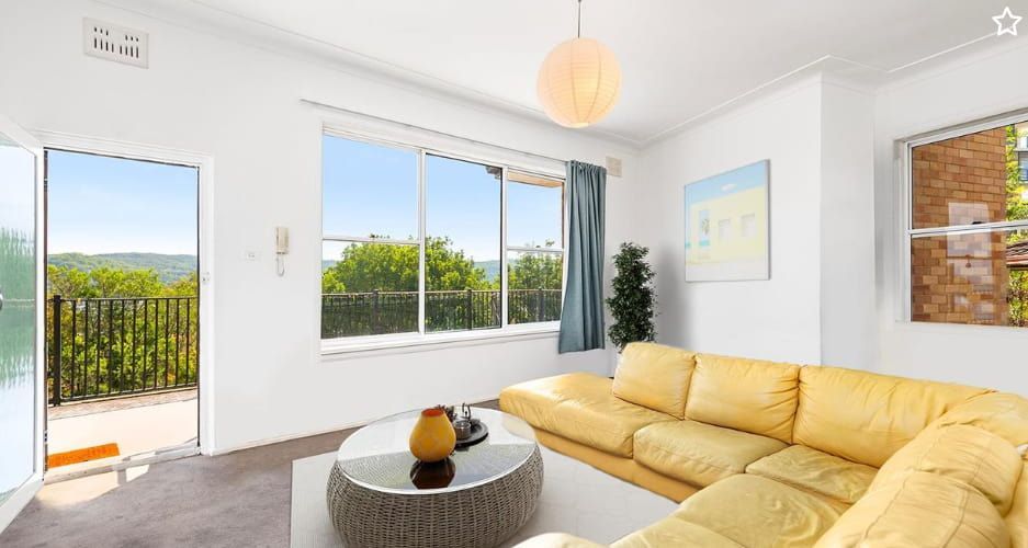 A living room with a yellow couch and a round coffee table — Maison Property Management in Mayfield, NSW