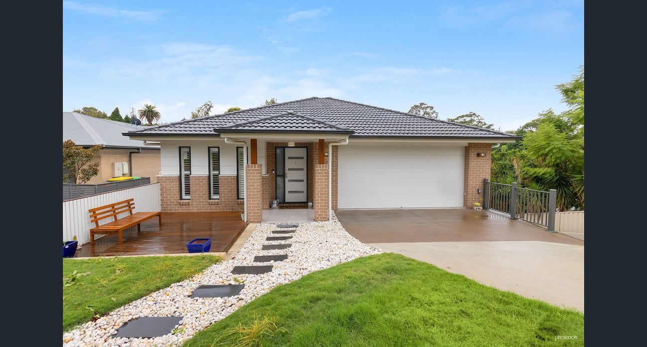 A House with A White Garage Door and A Bench in Front of It — Maison Property Management in Waratah, NSW