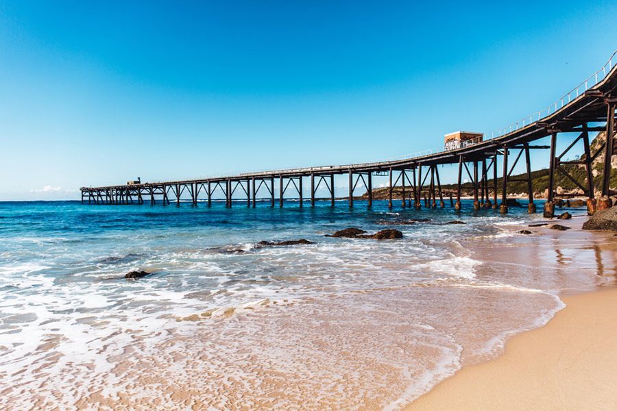 A Pier Leading Into the Ocean on A Sandy Beach — Maison Property Management in Lake Macquarie, NSW