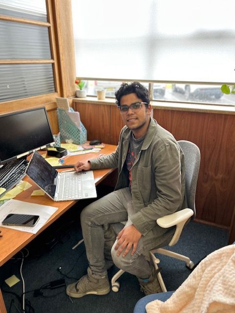 A man is Sitting at a Desk with a Laptop on it.
