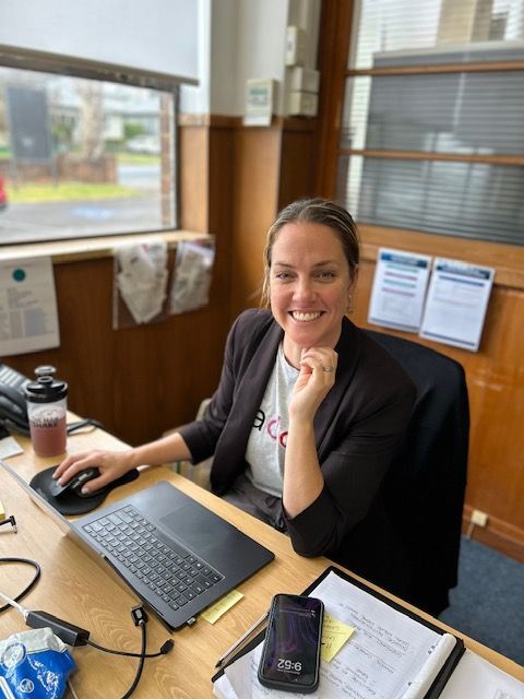 A Woman is Sitting at a Desk with a Laptop and Smiling