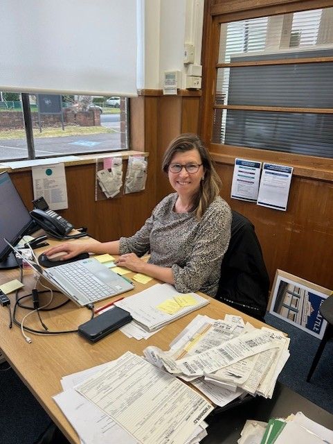 A Woman is Sitting at a Desk in Front of a Laptop Computer.