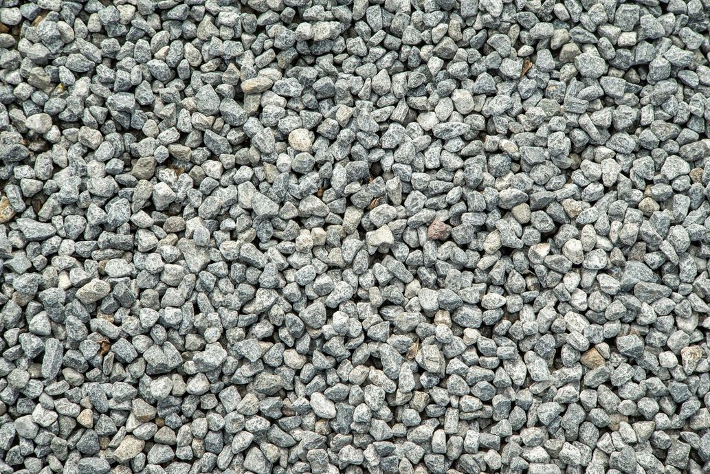 Gray gravel, small and irregularly shaped, covers a surface.