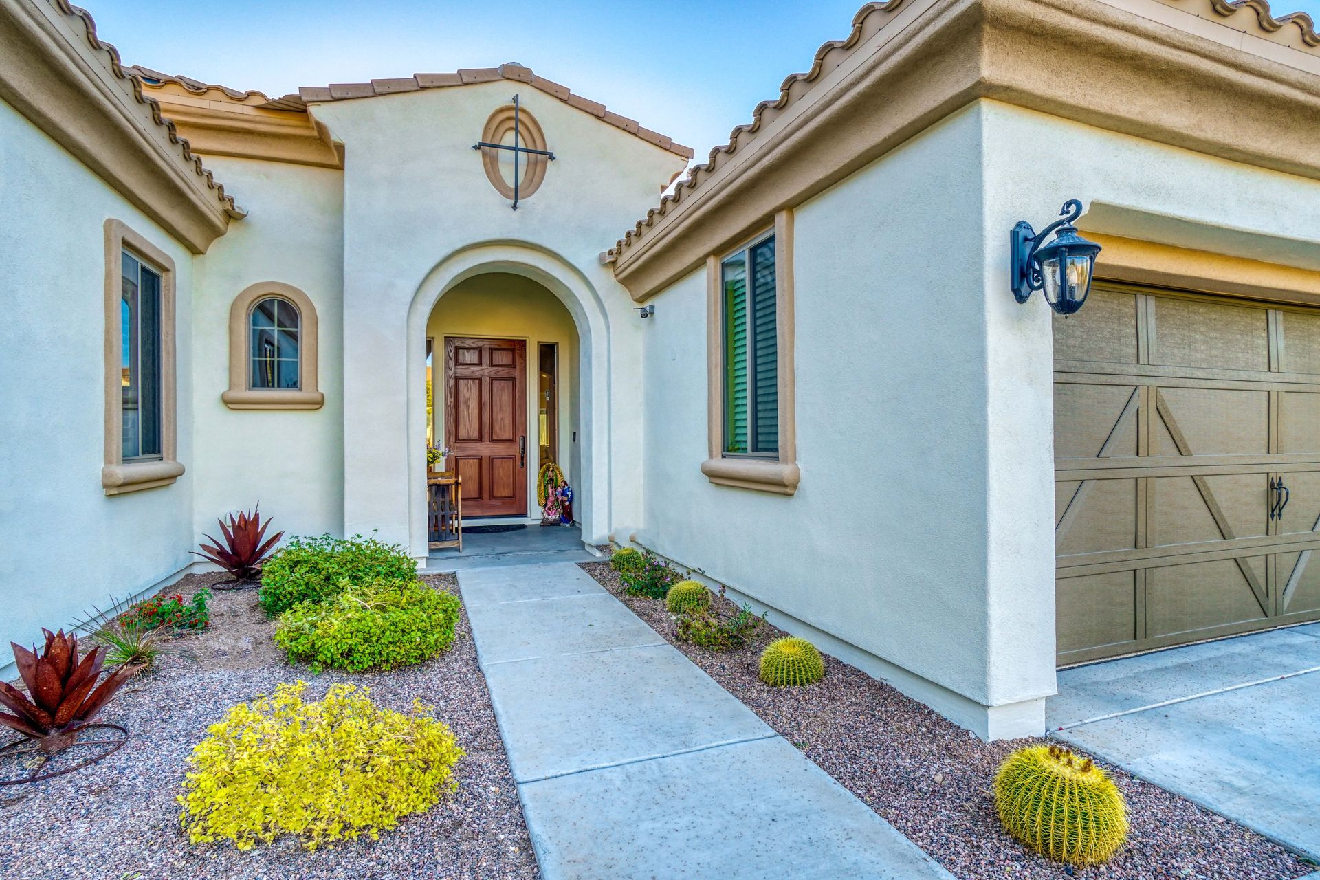 A stucco house with a light-colored exterior, walkway, and landscaping.