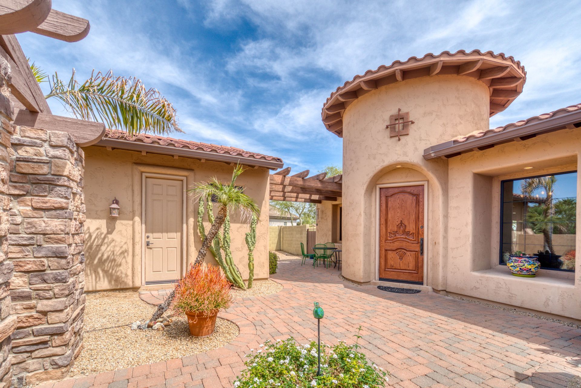 Courtyard with brick patio, stucco buildings, and a round tower entry.