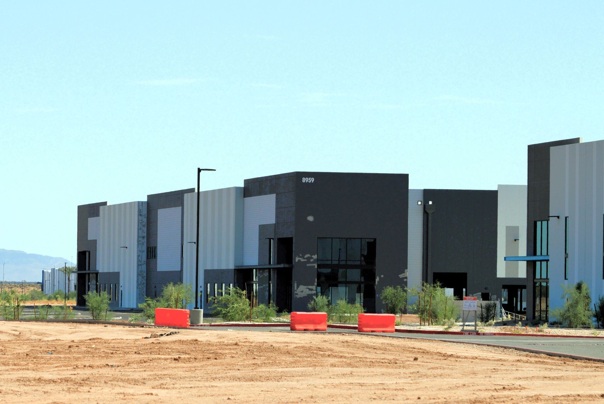 Modern industrial buildings with varying shades of gray and black against a desert landscape.