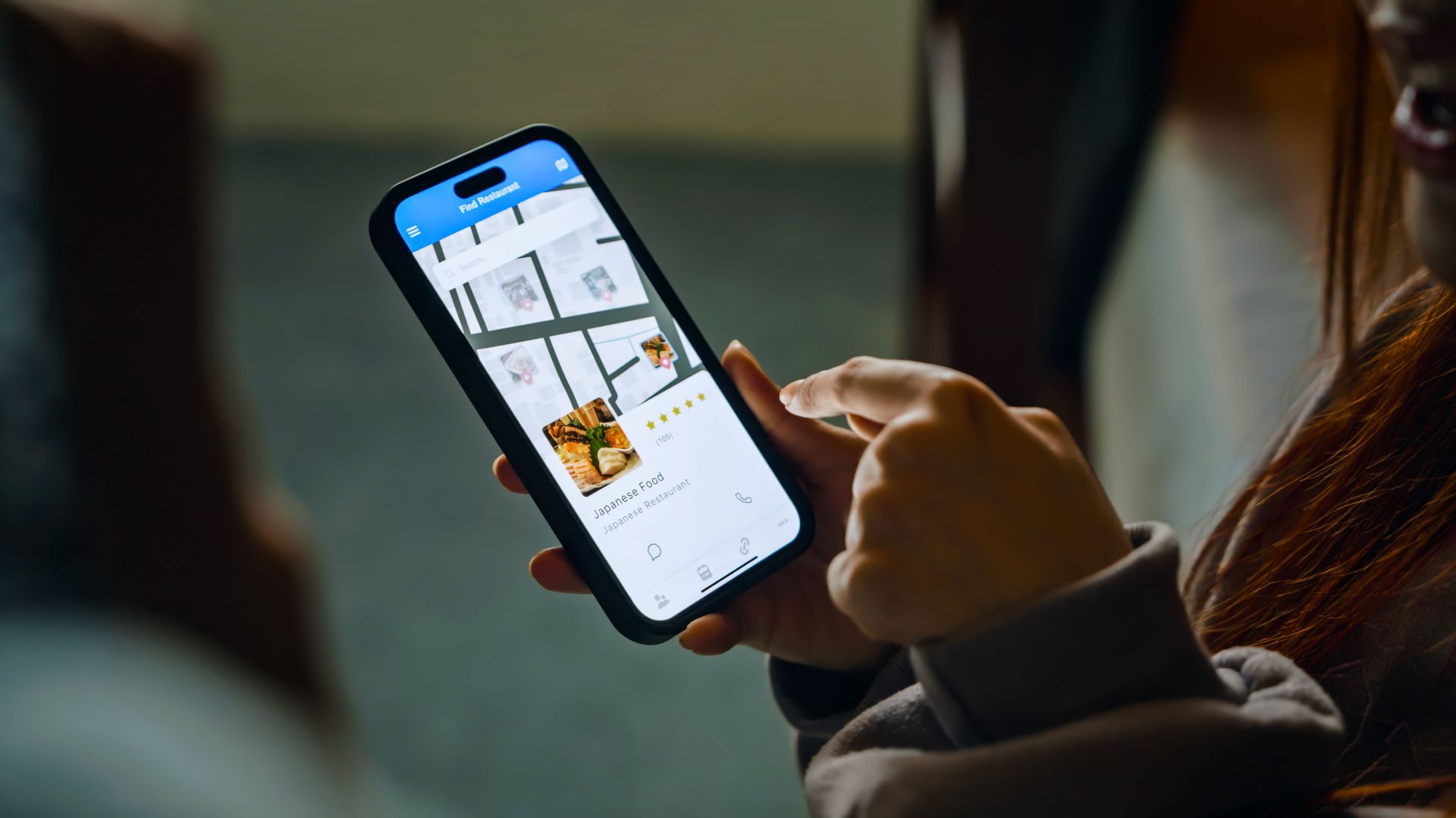 A woman is holding a cell phone in her hand.