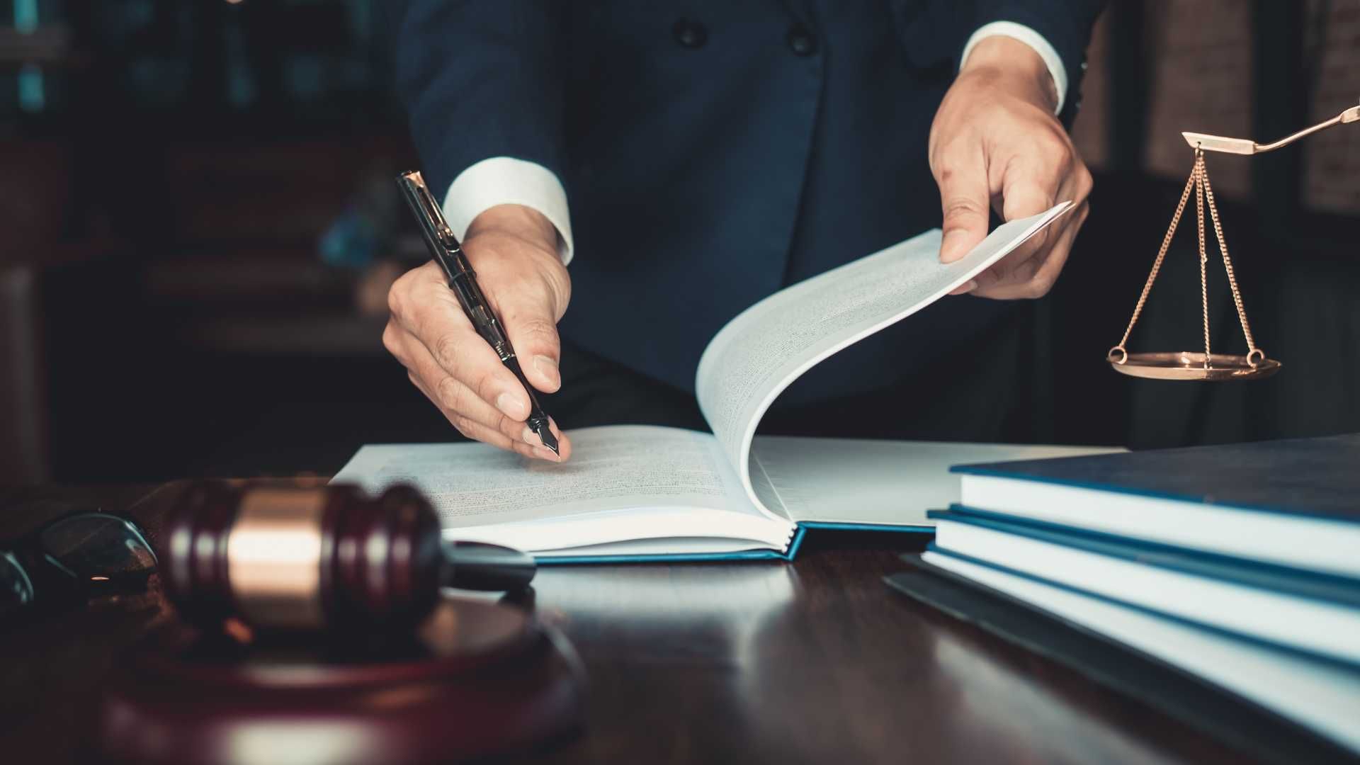 A judge is sitting at a desk writing on a piece of paper.