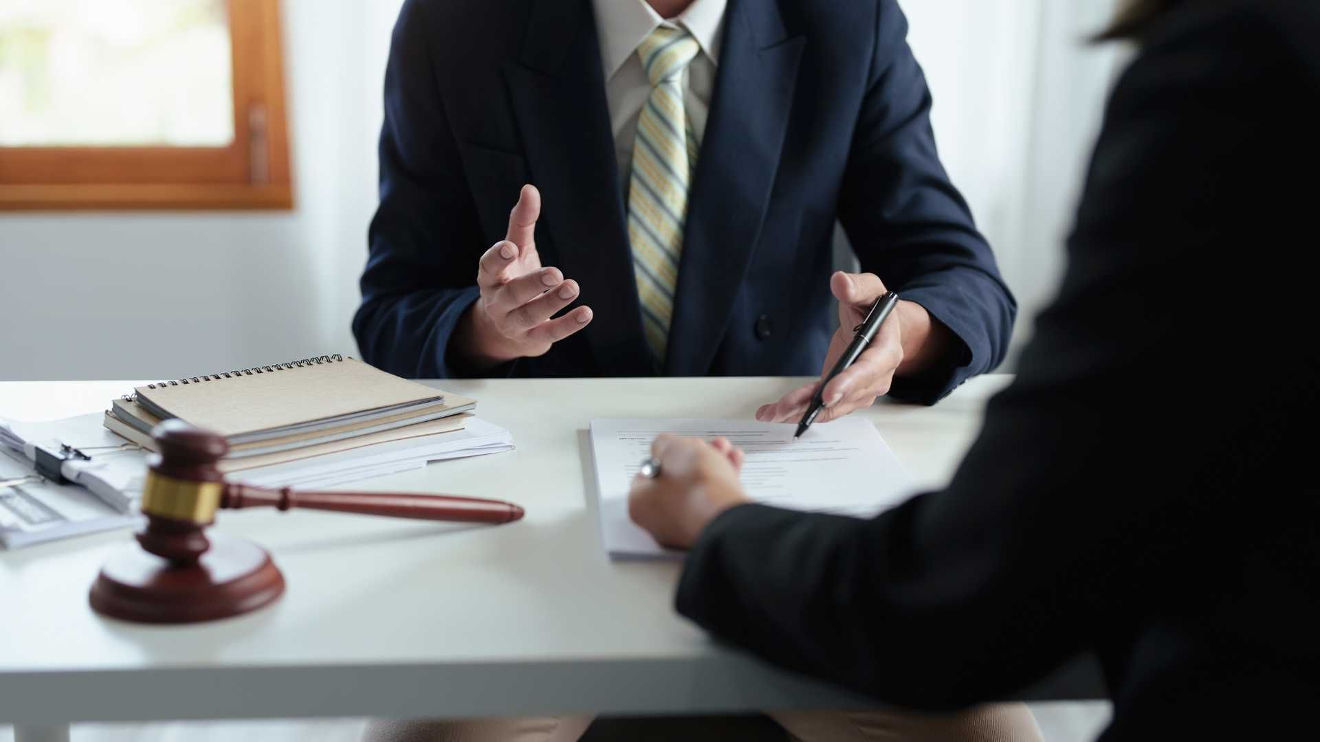 A man in a suit and tie is sitting at a table talking to a woman.