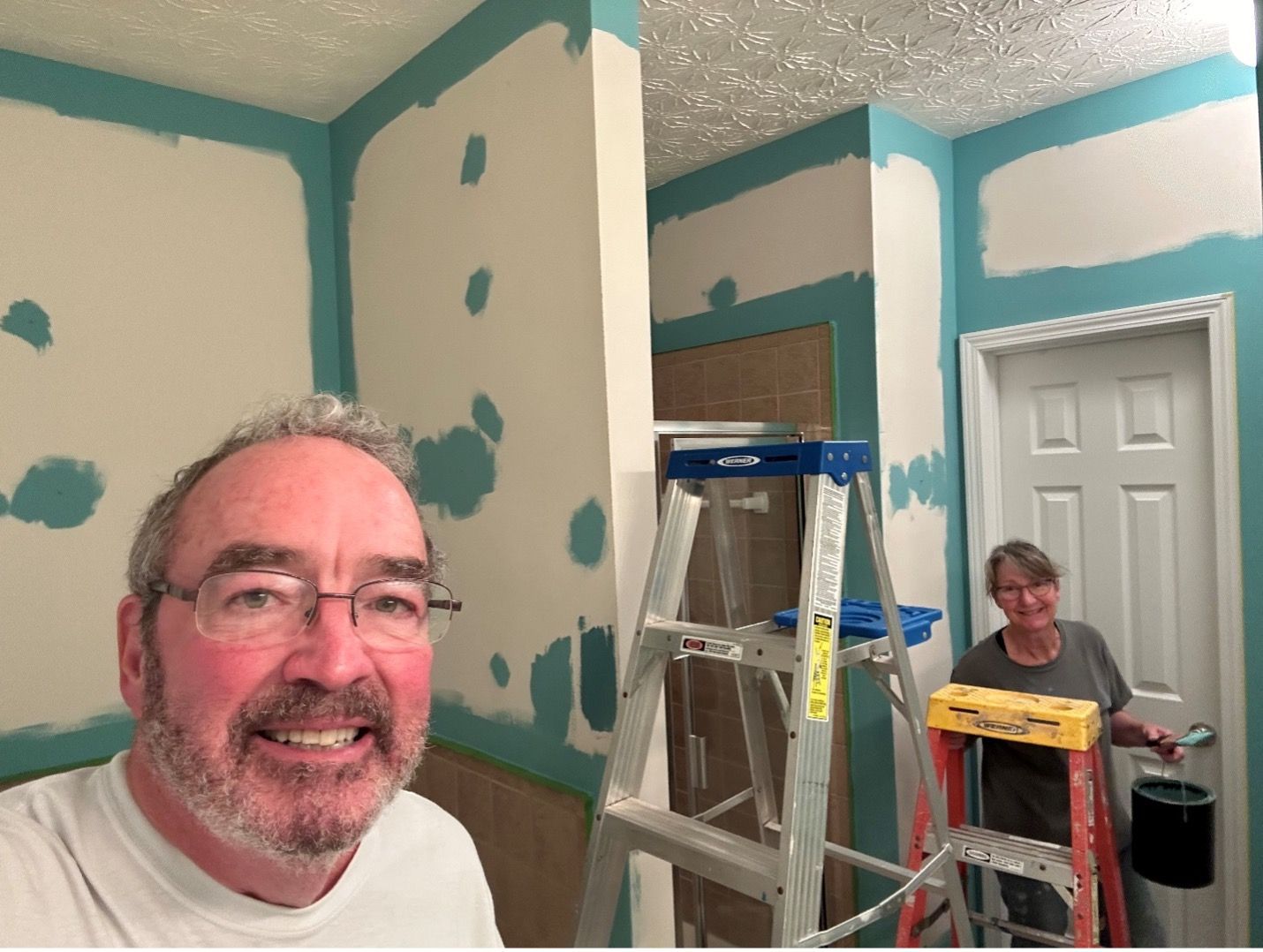 A man and a woman are painting a room together