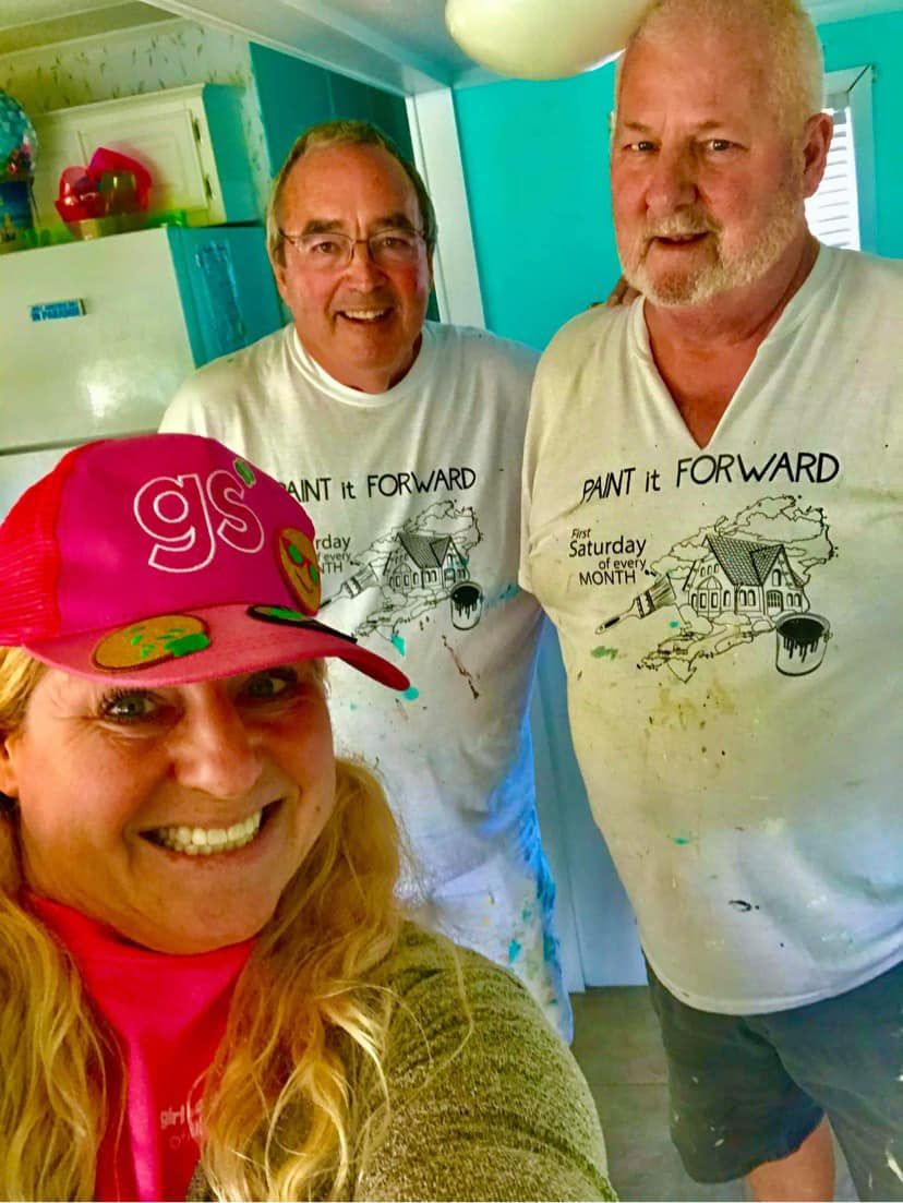 A woman wearing a pink hat is posing for a picture with two men.