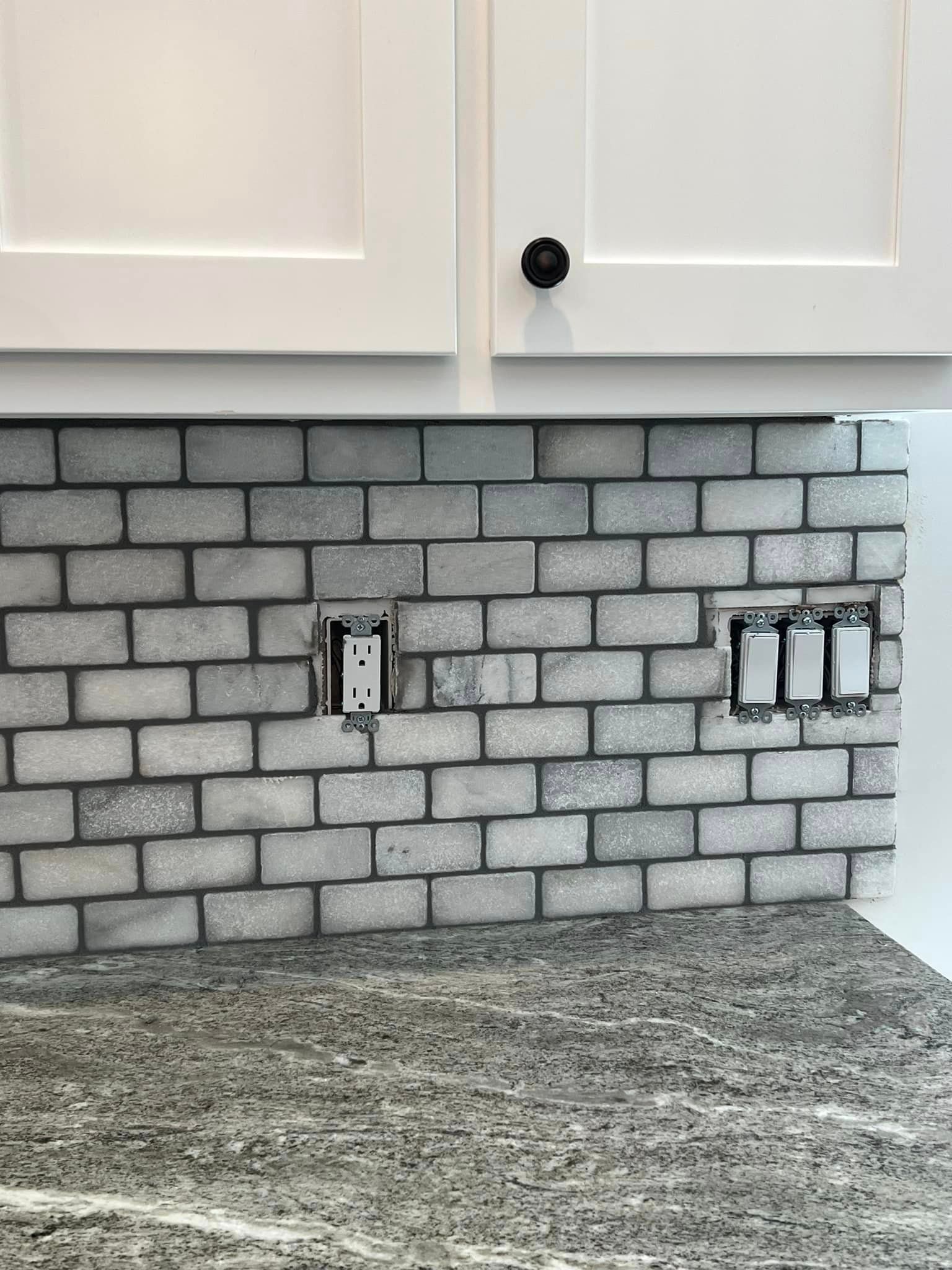 A kitchen with a brick wall and a granite counter top.