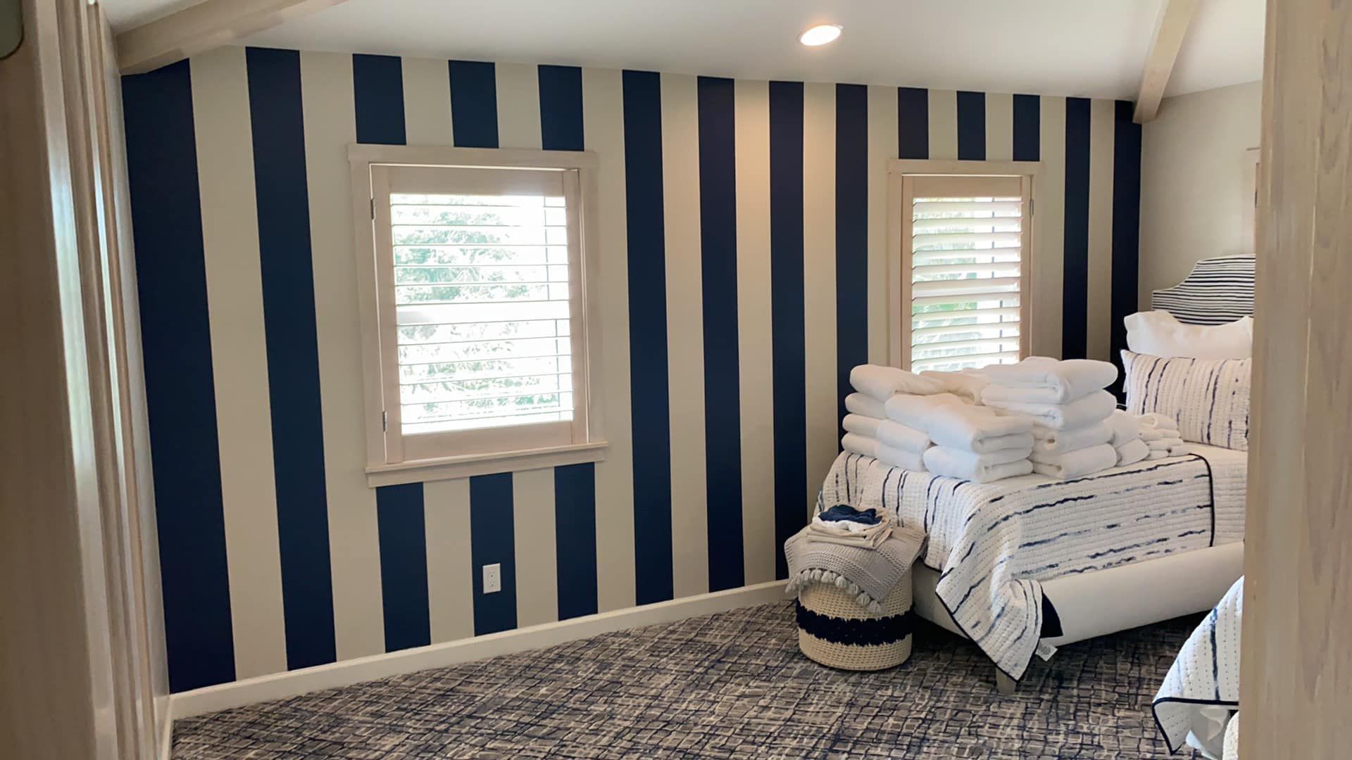 A bedroom with blue and white striped walls and a bed.
