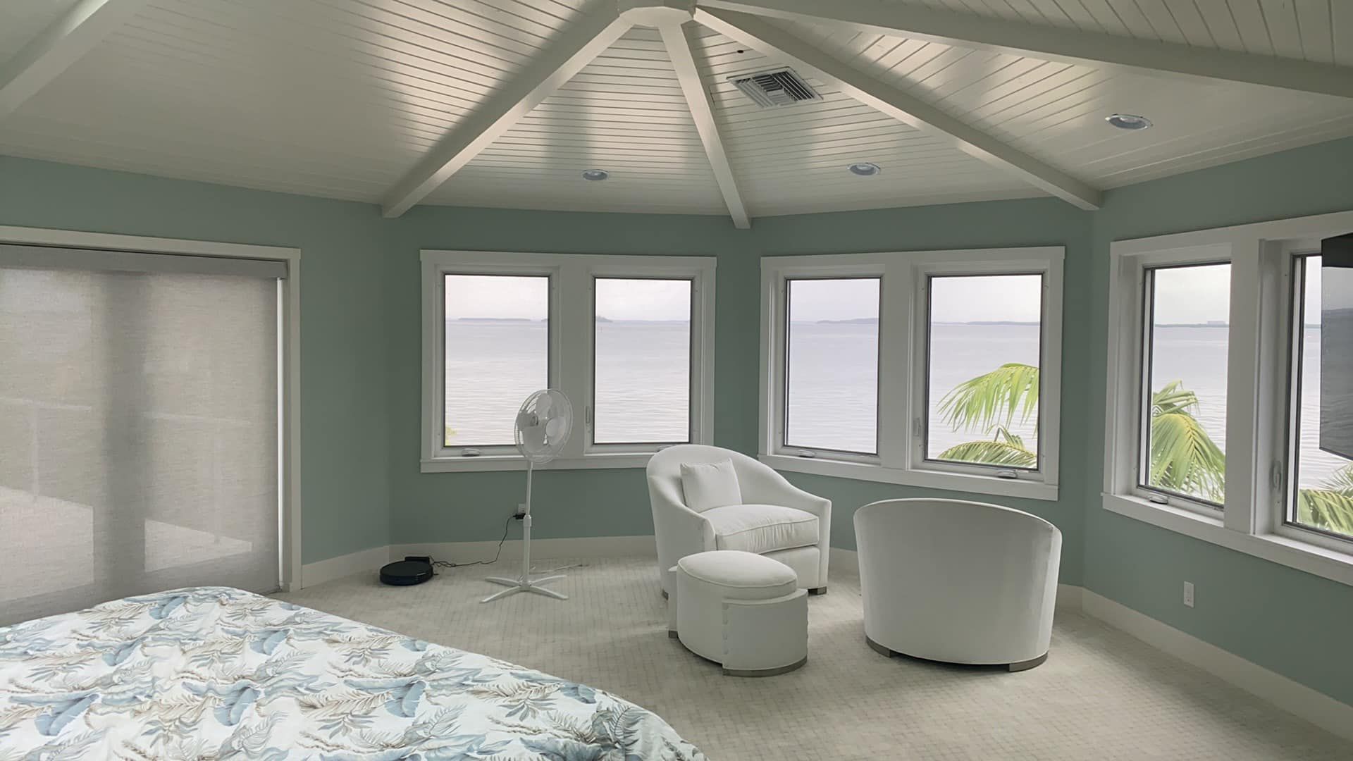 A bedroom with lots of windows and a view of the ocean