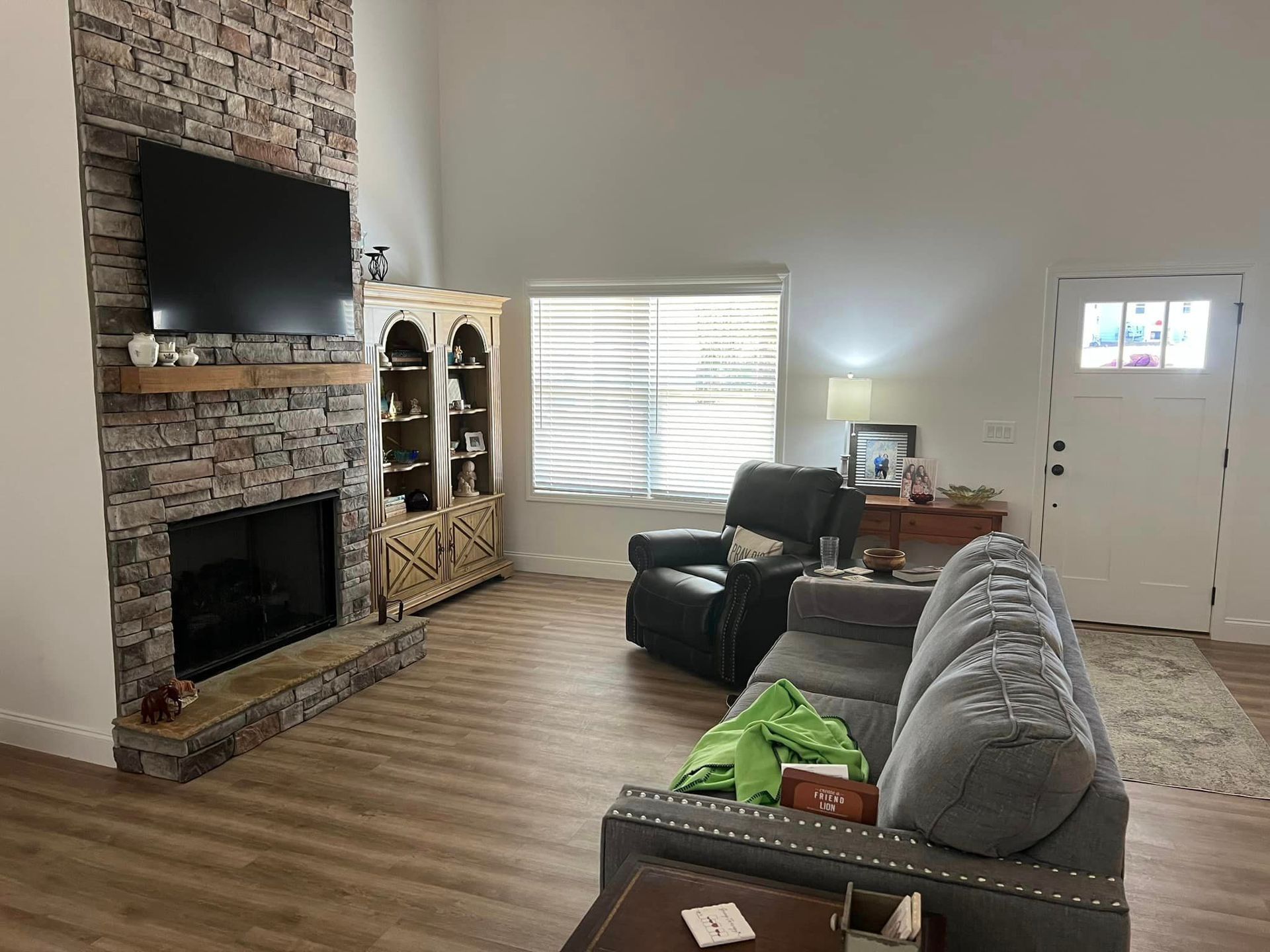 A living room with a couch , chair , television and fireplace.