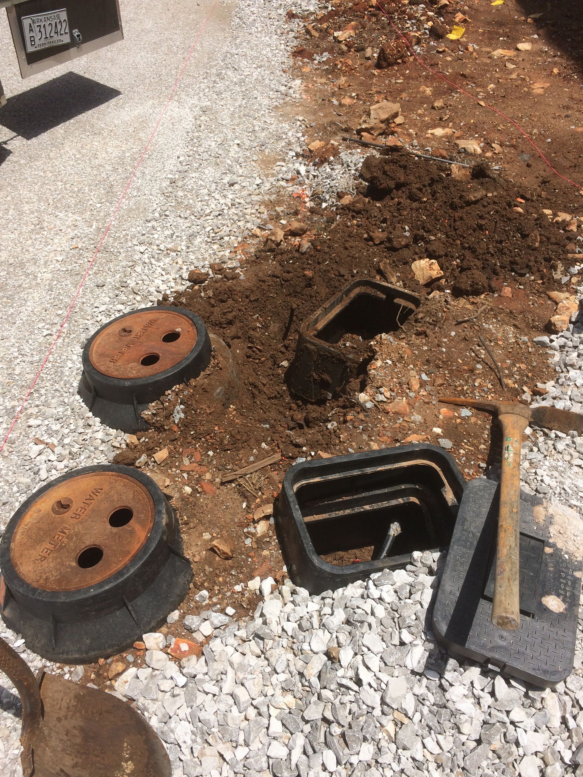 A manhole cover is being installed in a gravel area.
