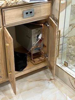 A wooden cabinet with the doors open and a copper pipe coming out of it.