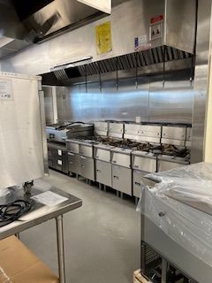 A kitchen with a lot of stainless steel appliances and a table.