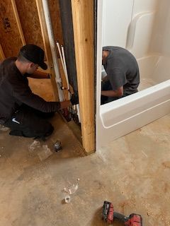Two men are working on a bathtub in a bathroom.