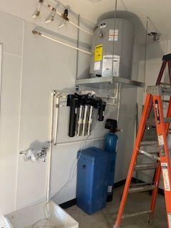 A room with a water heater and a ladder in it.