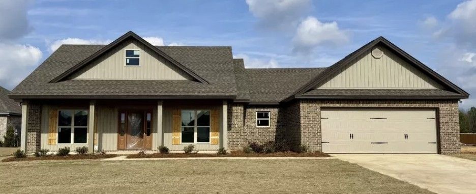 Single-story brick house with a two-car garage and front porch under a cloudy sky