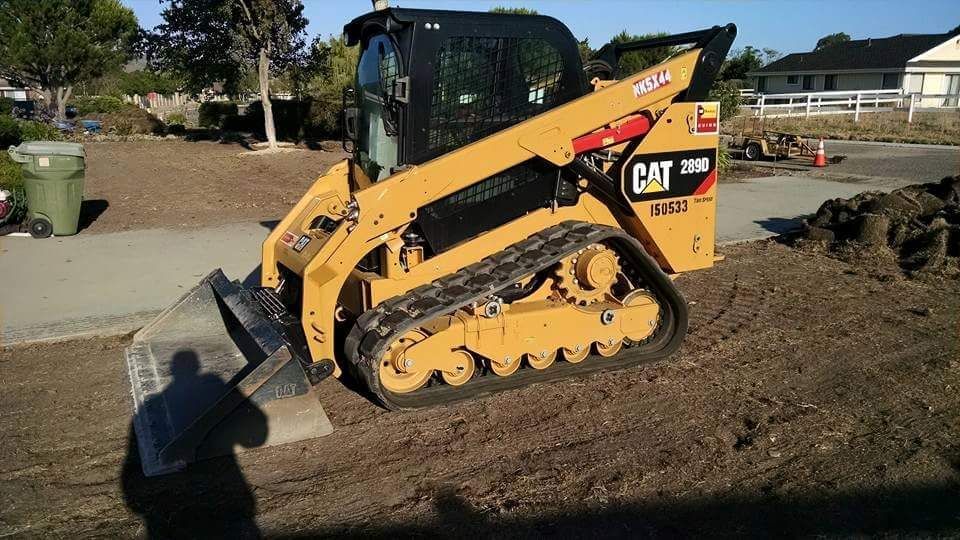 A cat skid steer is sitting on top of a dirt field.