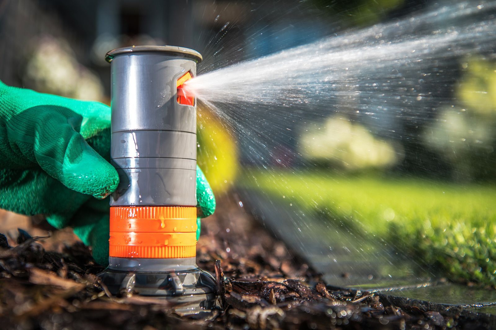 A person is watering a lawn with a sprinkler.