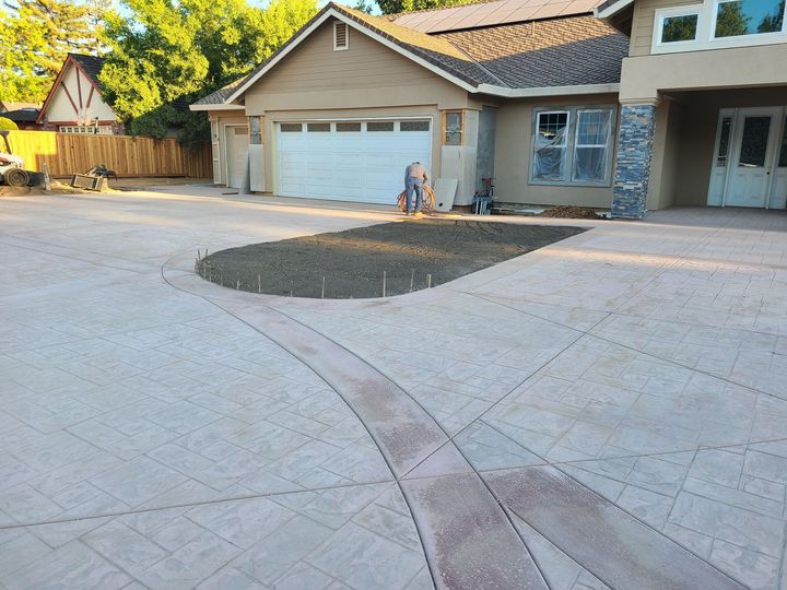Suburban driveway with a garage, stone paving, and two children sitting near the house.