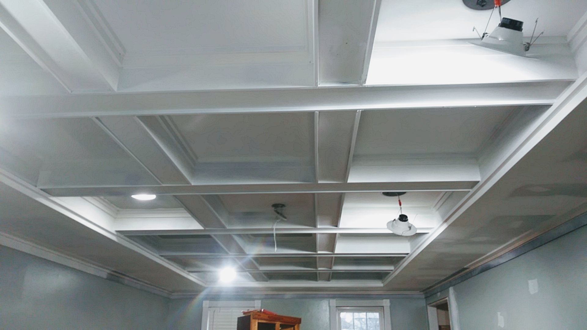 White coffered ceiling with recessed lighting in a room with light blue walls.