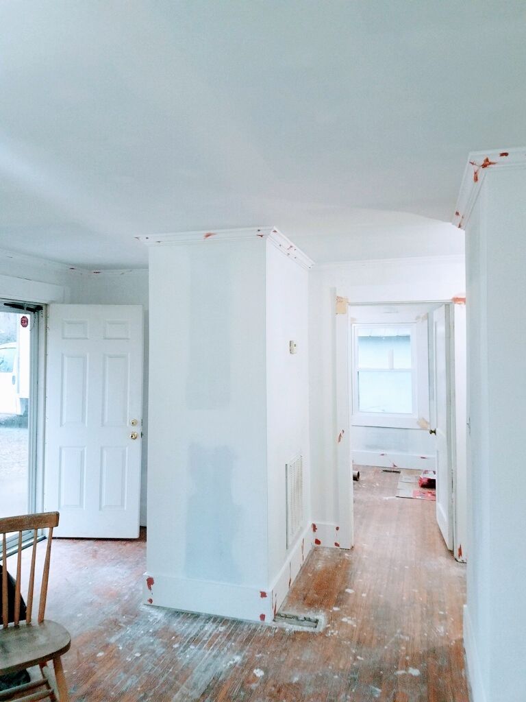Interior of a house under renovation with white walls, exposed wood floors, and open doorways.
