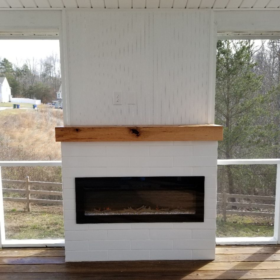 White brick fireplace with wooden mantel, black fireplace insert, and white paneling.