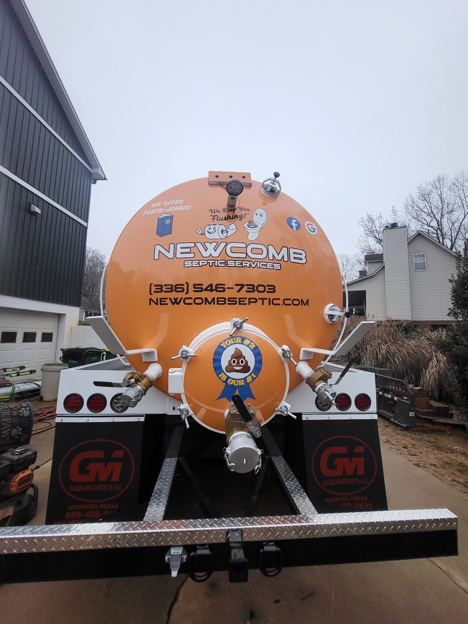 Orange Newcomb septic tank truck with branding, parked in front of a building.