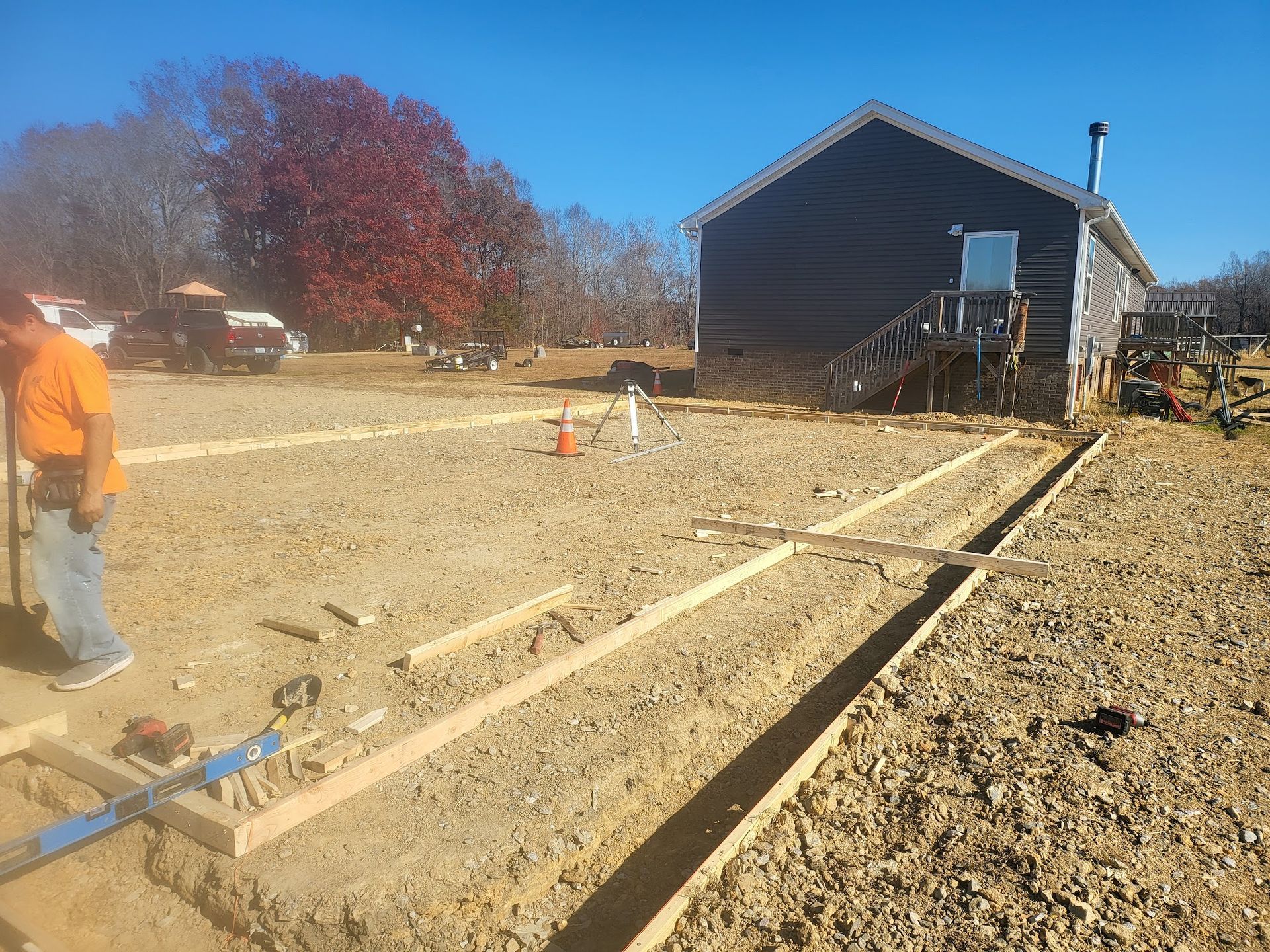 Construction site with a worker, lumber forms, and a log cabin style building.