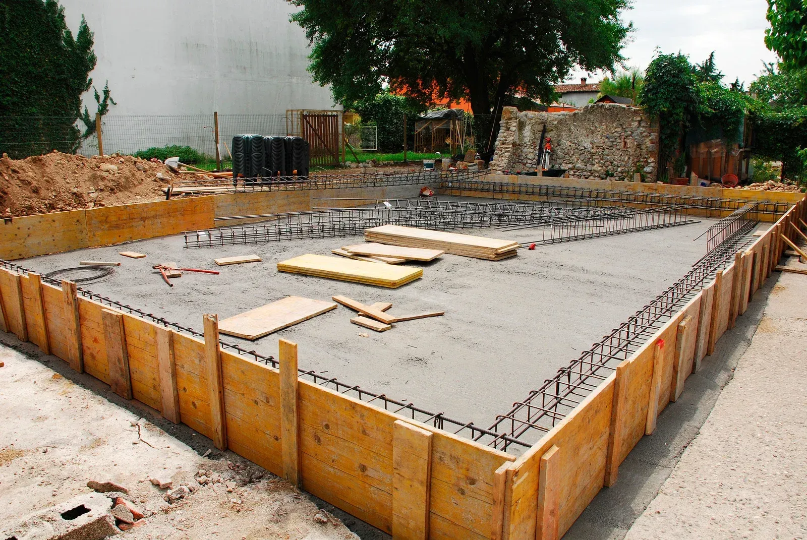 Concrete foundation in wooden frame with rebar, under construction. Outdoor setting.