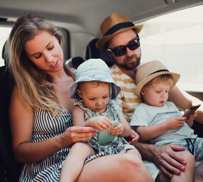 Family of four in car, parents and toddlers. Mother looking at baby, father at other child.