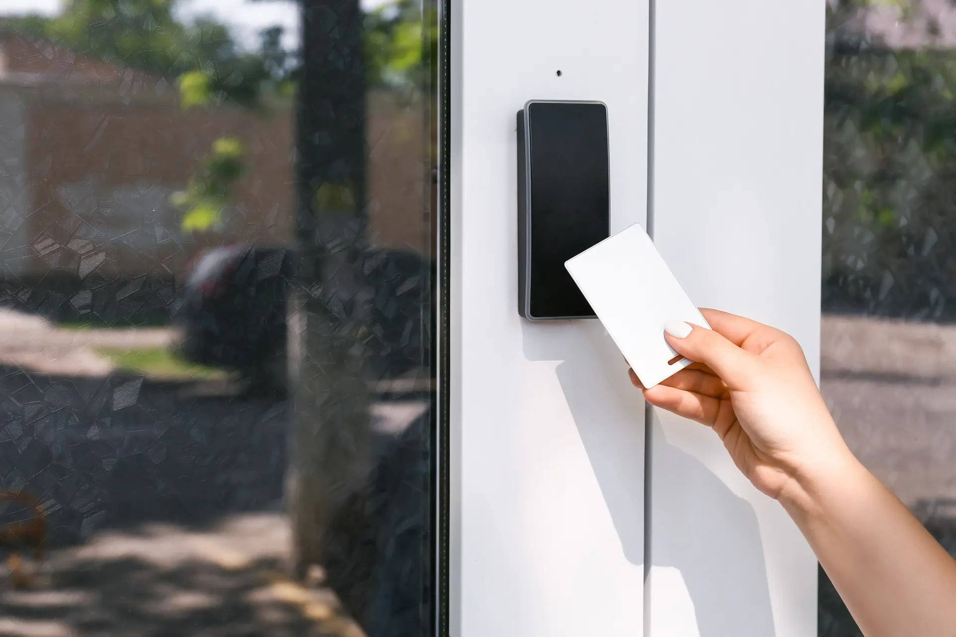 A person using an RFID card to gain entry via a modern door access system in Malaysia.