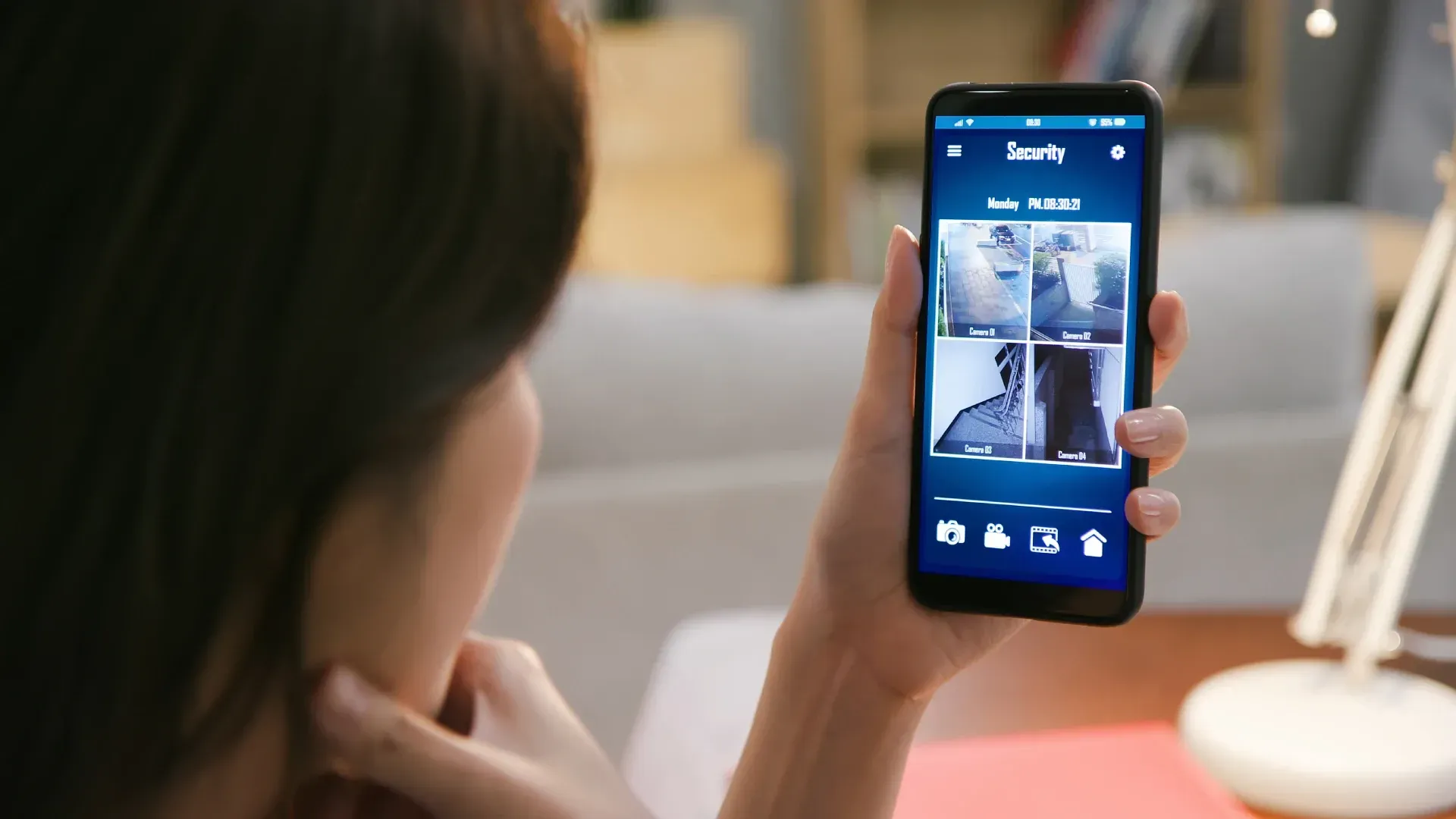 A person viewing home security camera feeds on a smartphone app provided by a professional security 