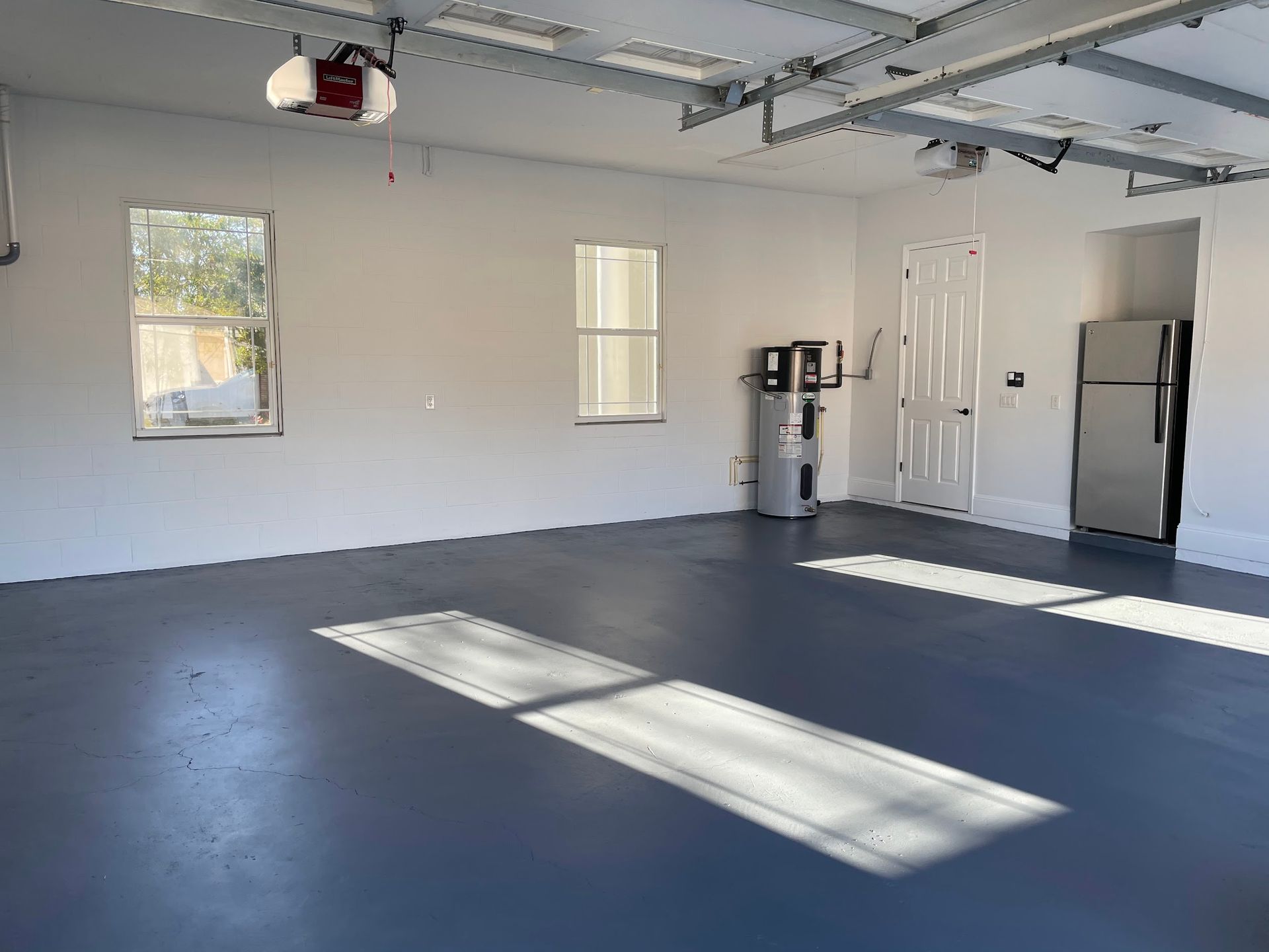 An empty garage with a blue floor and white walls.