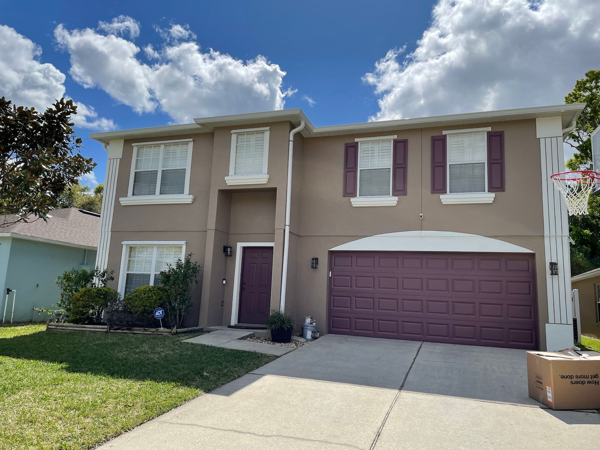 A house with a purple garage door and a basketball hoop in front of it.