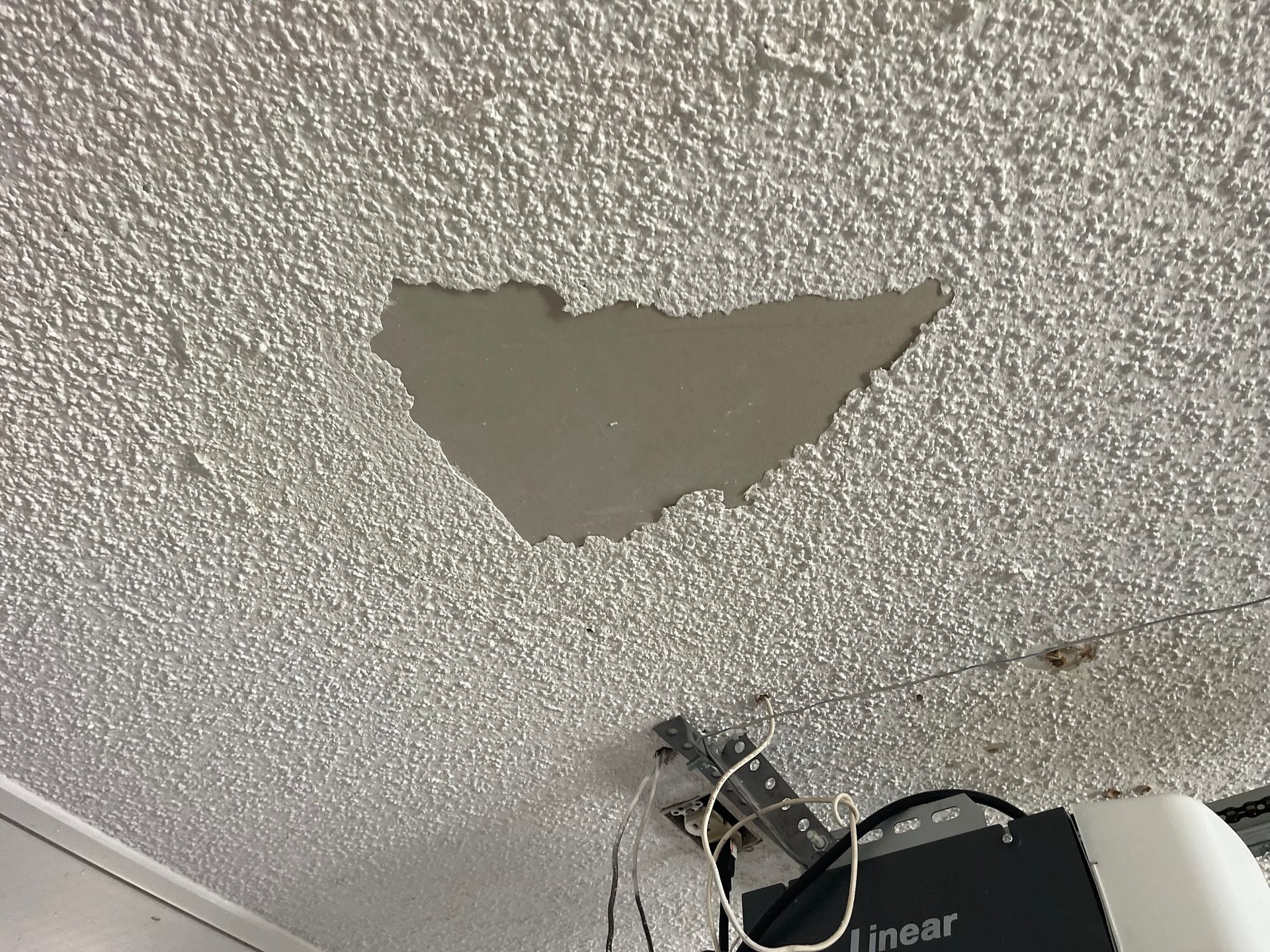 A ceiling with a hole in it and a garage door opener.