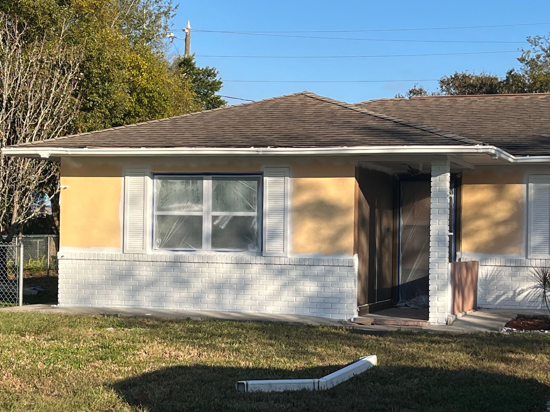 A yellow and white house with a brown roof