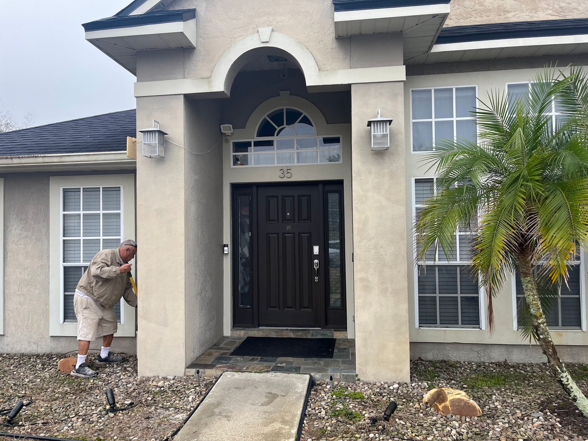 A man is standing in front of a house with a black door.