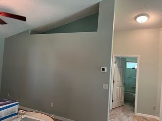 A living room with a ceiling fan and a doorway leading to a bathroom.
