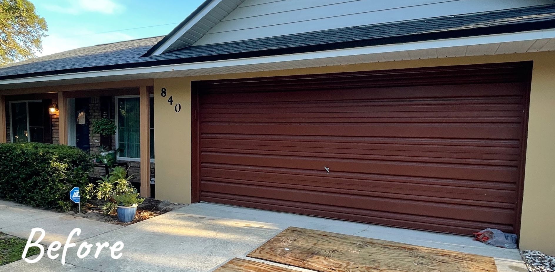 A before picture of a house with a red garage door.