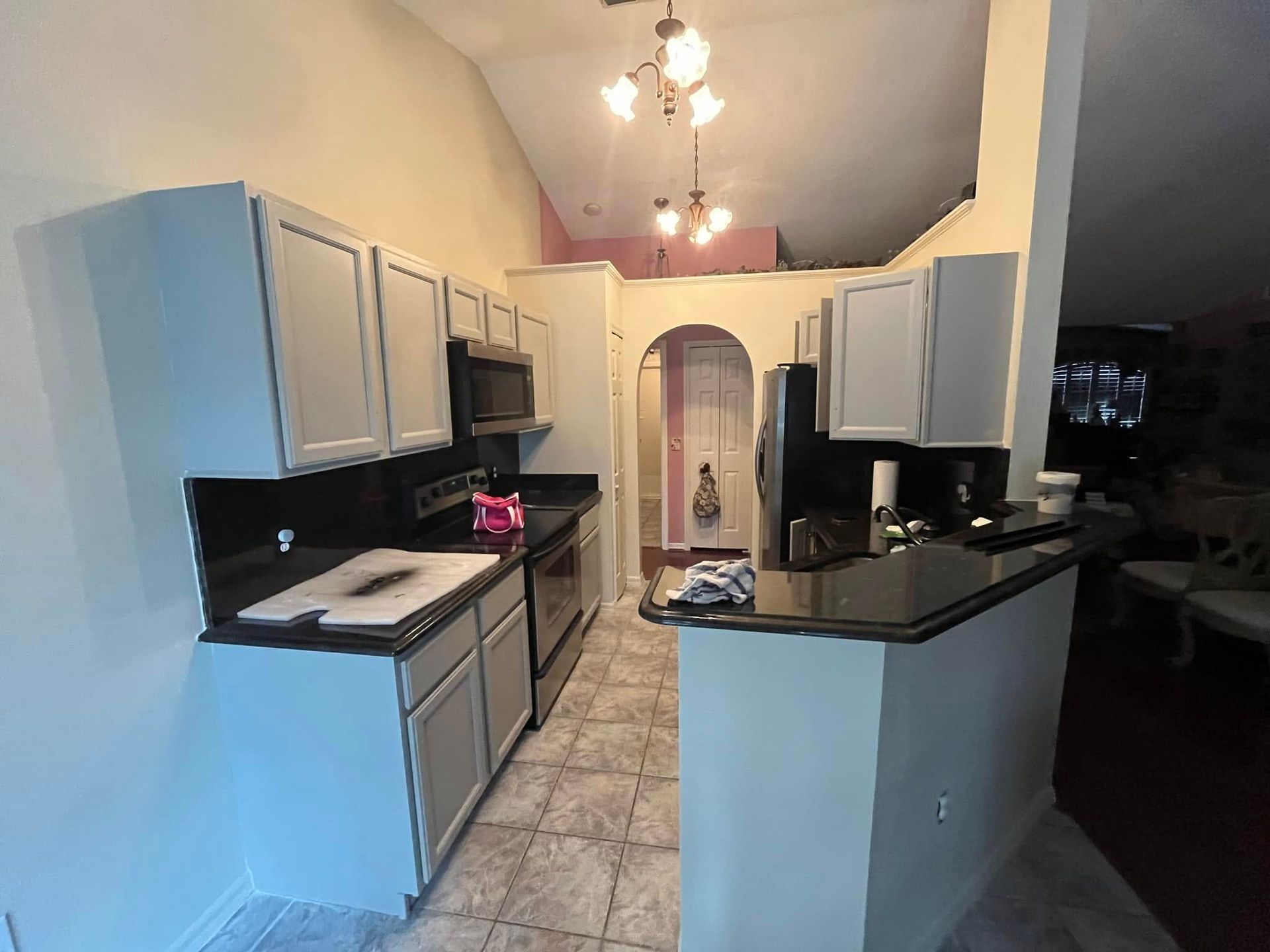A kitchen with white cabinets and black counter tops.