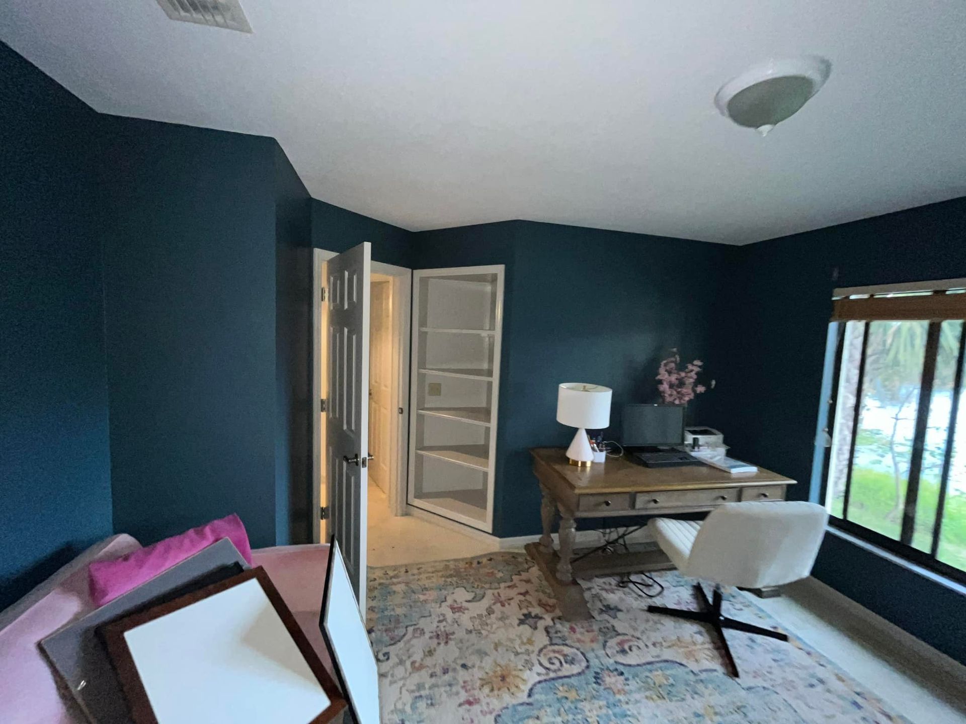 A room with dark blue walls and a desk and chair.