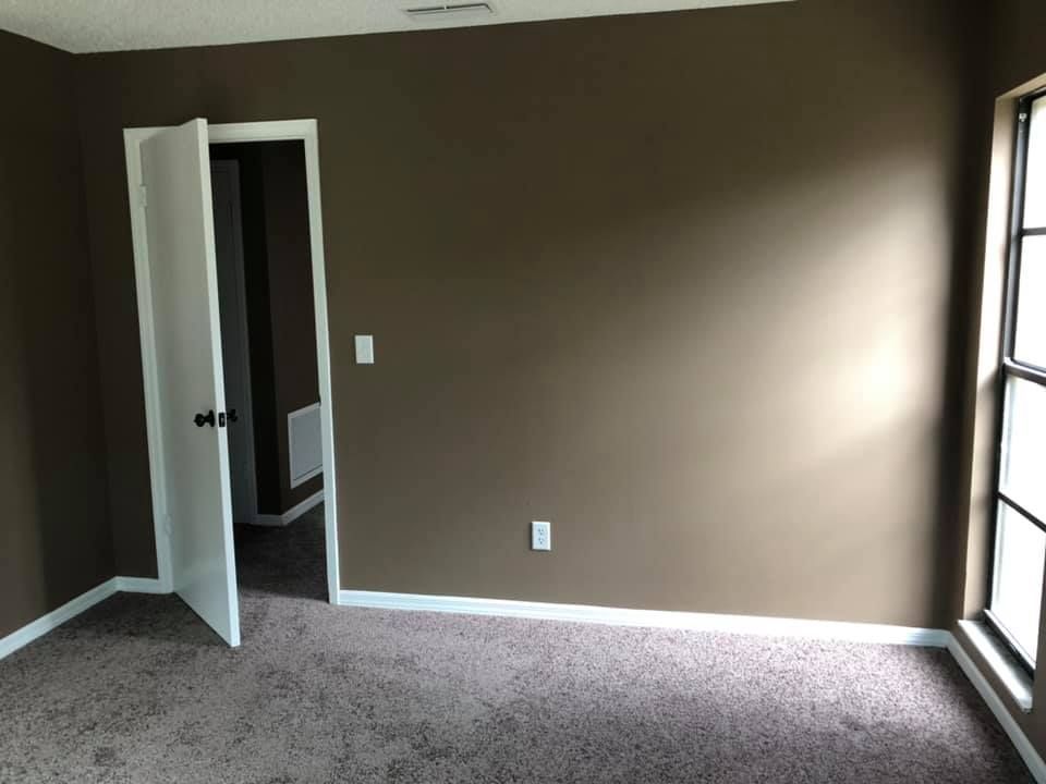 An empty room with brown walls and a carpeted floor