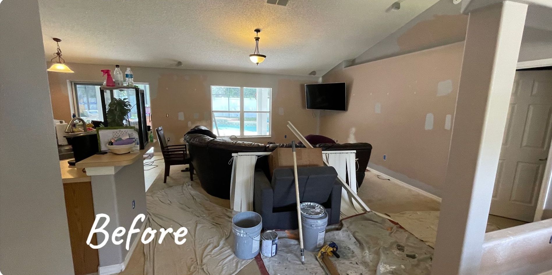 A living room with a couch and a television before being painted.
